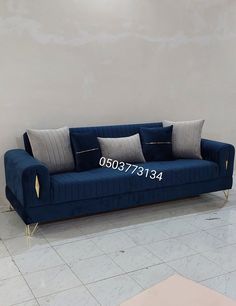 a blue couch sitting in front of a wall with pillows on it's back