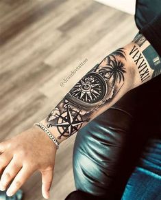 a man's arm with a compass and palm tree tattoo on the left forearm