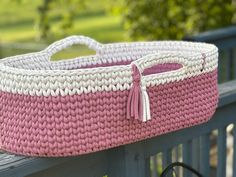 a pink and white basket sitting on top of a wooden bench