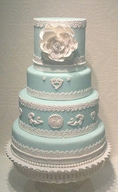 a three tiered blue wedding cake with white flowers on top