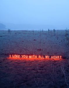 a neon sign that says i love you with all my heart on it in the middle of a field