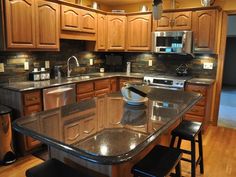 a large kitchen with wooden cabinets and black counter tops, along with an island in the middle