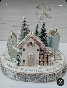 there is a small christmas village on top of a tree stump with snowflakes