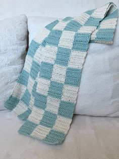 a crocheted blanket sitting on top of a white couch next to a pillow