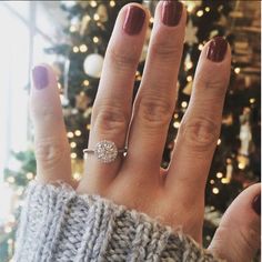 a woman's hand with a ring on it and a christmas tree in the background