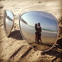 the reflection of two people in sunglasses on the beach