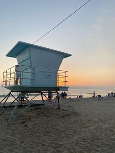 a lifeguard tower on the beach at sunset