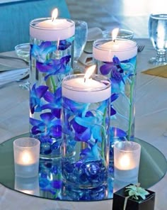 blue flowers and candles in glass vases on a table