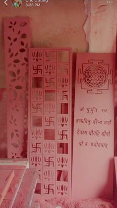 pink paper cut art work displayed in front of a wall with writing on the side