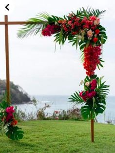 an outdoor wedding ceremony setup with flowers and greenery on the grass by the ocean