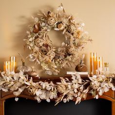 a wreath on top of a mantle next to candles