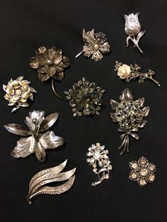 Lot of 11 Vintage silver tone flower inspired design brooch/pin. Mismatched lot, all are different from each other. 5 flower brooches are simple without rhinestones. 6 flower designs sparkle with the rhinestones. All of the rhinestones are intact. All latches on the backs were checked and all work. Great for Mother's Day gift, any special occasion present, or to be used in a craft project. Vintage Silver Flower Pins, Silver Brooch Pins For Costume Jewelry, Silver Costume Jewelry Pins Brooch, Silver Costume Jewelry Brooch Pins, Vintage Silver Rhinestone Pins, Silver Flower-shaped Brooches With Rhinestones, Pin Design, Rhinestone Brooches, Flower Brooch