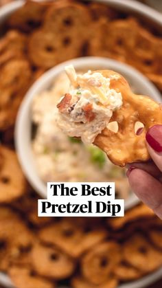 a hand holding up a cracker over a bowl of dip and onion rings with the words, the best pretzel dip