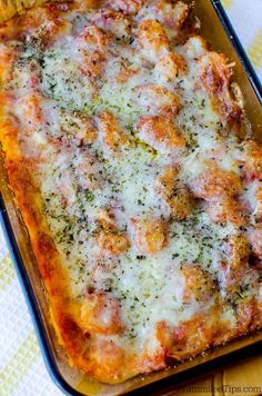 a casserole dish with meat and cheese on it sitting on a yellow table cloth