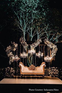 a couch sitting on top of a white table under a tree filled with lots of lights