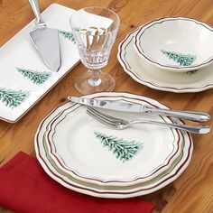 the place setting is set with silverware and pine - tree plates, forks and knives