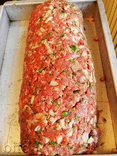 an uncooked meatloaf covered in sauce and herbs