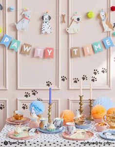 a table topped with plates and cups filled with cake next to a wall covered in animal themed decorations