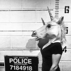 a fake unicorn head mounted to the side of a wall next to a police sign