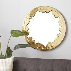 a living room with a brown couch and a gold plate on the wall next to a potted plant