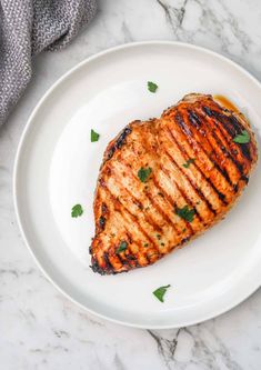 grilled chicken on a white plate with parsley