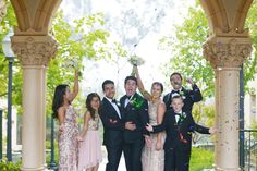 a group of people standing next to each other in front of an archway with confetti