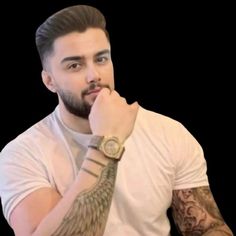 a man with tattoos and a watch on his wrist is looking at the camera while holding his hand to his chin