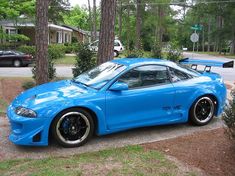 a blue sports car parked in front of some trees