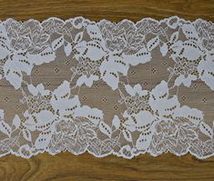 a white lace with flowers and leaves is on a wooden surface, ready to be used as a table runner