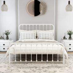 a white bed sitting in a bedroom next to two nightstands and a round mirror