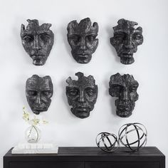 a black table topped with lots of different types of masks on it's wall