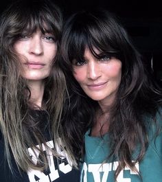 two beautiful women standing next to each other in front of a black background with long hair