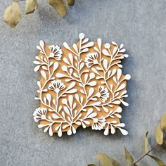 an intricately designed piece of wood sitting on top of a cement floor next to leaves