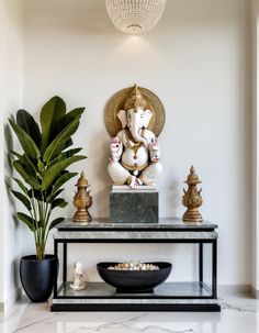 an elephant statue sitting on top of a table next to a potted plant and bowl