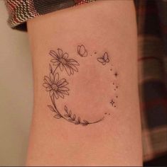 a woman's tattoo with daisies and butterflies on the side of her thigh