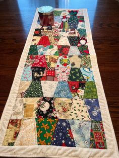 a table runner made out of old quilts on a wooden floor with a jar of jam