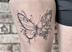 a black and white photo of a butterfly tattoo on the right thigh, next to a woman's leg