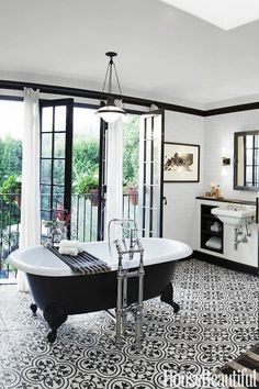 a bathroom with black and white tile flooring and an old fashioned bathtub in the center