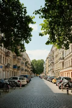 an empty street lined with parked cars and bicycles on both sides, surrounded by tall buildings