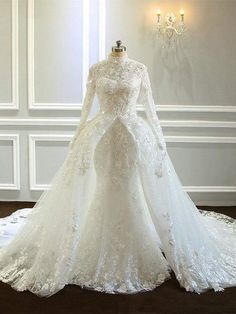 a white wedding gown on display in a room with chandelier and wall lights