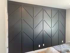 a bed sitting in front of a black wall with arrows painted on it's side