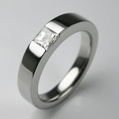 a ring with a princess cut diamond set in the center, on a white background