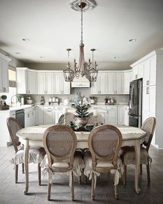 a dining room table with four chairs and a chandelier hanging from the ceiling