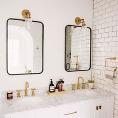 a bathroom with two sinks, mirrors and white tiles on the wall above them are gold faucets