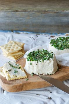 there are crackers and cheese on the cutting board next to each other with herbs sprinkled all over them