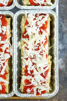 four pans filled with lasagna shells covered in marinara sauce and parmesan cheese