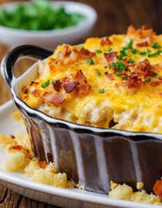 a casserole dish with bacon and green onions on the side, ready to be eaten