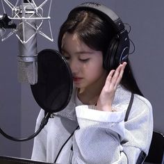 a young woman wearing headphones while sitting in front of a microphone