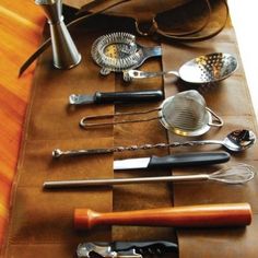 an assortment of kitchen utensils are laid out on a leather tablecloth with spoons and graters