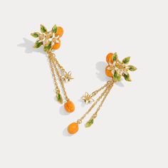 Infuse your style with a touch of nature-inspired elegance with our Golden Plum Drop Earrings, a striking accessory that captures the essence of botanical beauty. These exquisite earrings are meticulously crafted, featuring delicate plum motifs adorned with vibrant orange and green enamel. Each earring showcases a cluster of golden plums and leaves, accented by petite white blossoms that cascade down on fine golden chains. Whether you're dressing up for a special occasion or adding a unique touc Orange Blossom Earrings, Elegant Orange Flower Earrings, Elegant Orange Flower Earrings For Gift, Orange Flower Earrings, Golden Plum, Osmanthus Fragrans, Astrology Jewelry, Plum Flowers, Fruit Jewelry